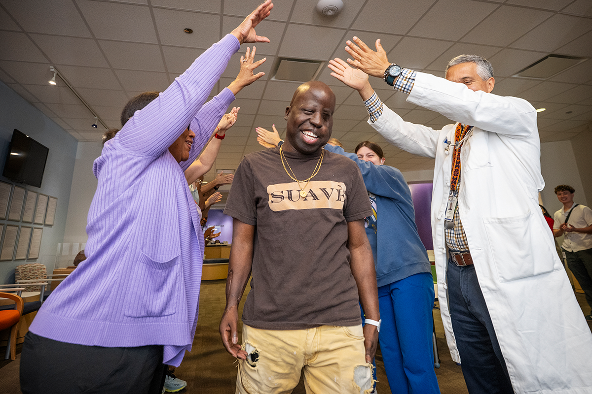 London Wallace smiling as he walks through a celebratory arch created by his doctors, nurses, and care team during his bell ringing ceremony at Texas Children's Hospital.